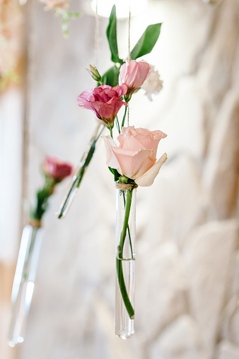 Composition of violet, pink flowers, greenery, herbs in glass vases and bulbs hanging on a wedding ceremony on photo zone. Wedding ceremony.