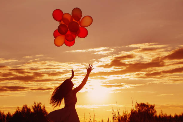 istock young women with balloons at sunset 935351034