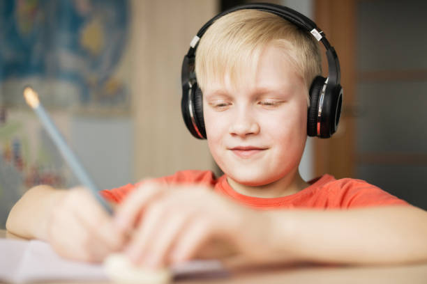 istock Boy in headphones writing and smiling. 935351264