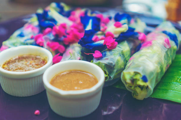 Fresh Rolls with rice noodles wrapped in lettuce and rice paper with thai herbs, cucumber, marinated carrot and banana flower with with peanut sauce is shown.