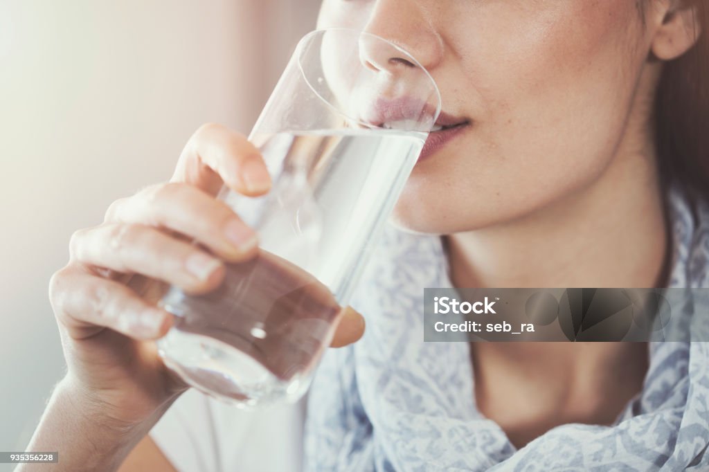 Giovane donna che beve puro bicchiere d'acqua - Foto stock royalty-free di Acqua