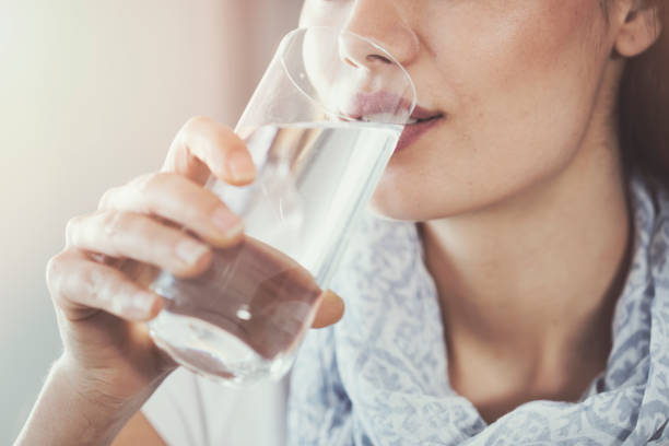 молодая женщина пьет чистый стакан воды - испытывающий жажду стоковые фото и изображения
