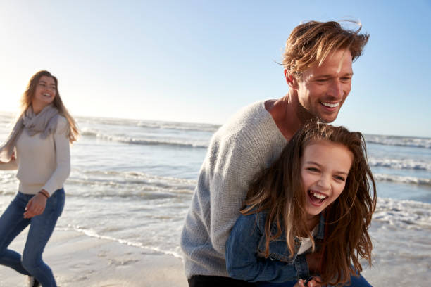 istock Parents With Daughter Having Fun On Winter Beach Together 935359718
