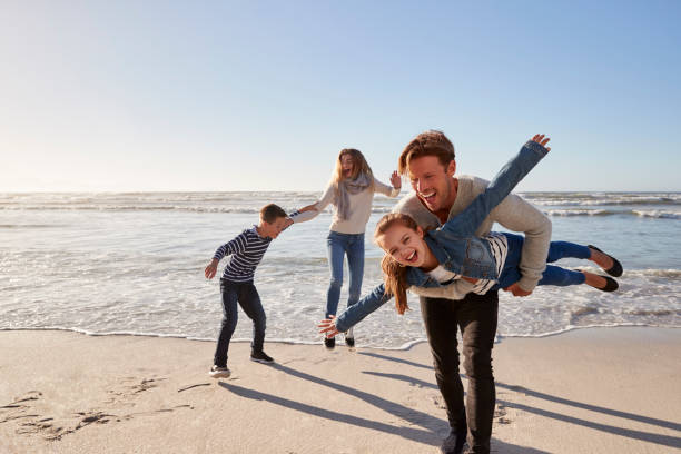 eltern mit kindern gemeinsam spaß am winter-strand - family four people smiling autumn stock-fotos und bilder