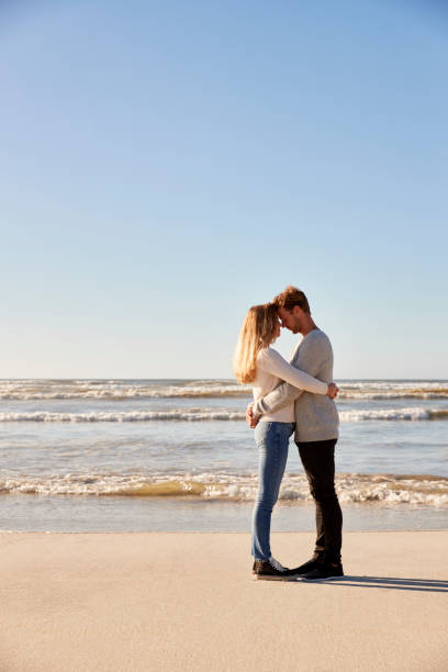 istock Romantic Couple Embracing On Winter Beach 935359934