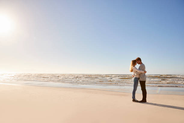 istock Romantic Couple Embracing On Winter Beach 935360020