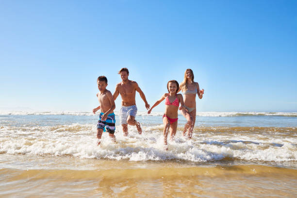 famille en vacances de plage d’été à court de mer vers la caméra - swimming trunks swimwear summer bikini photos et images de collection