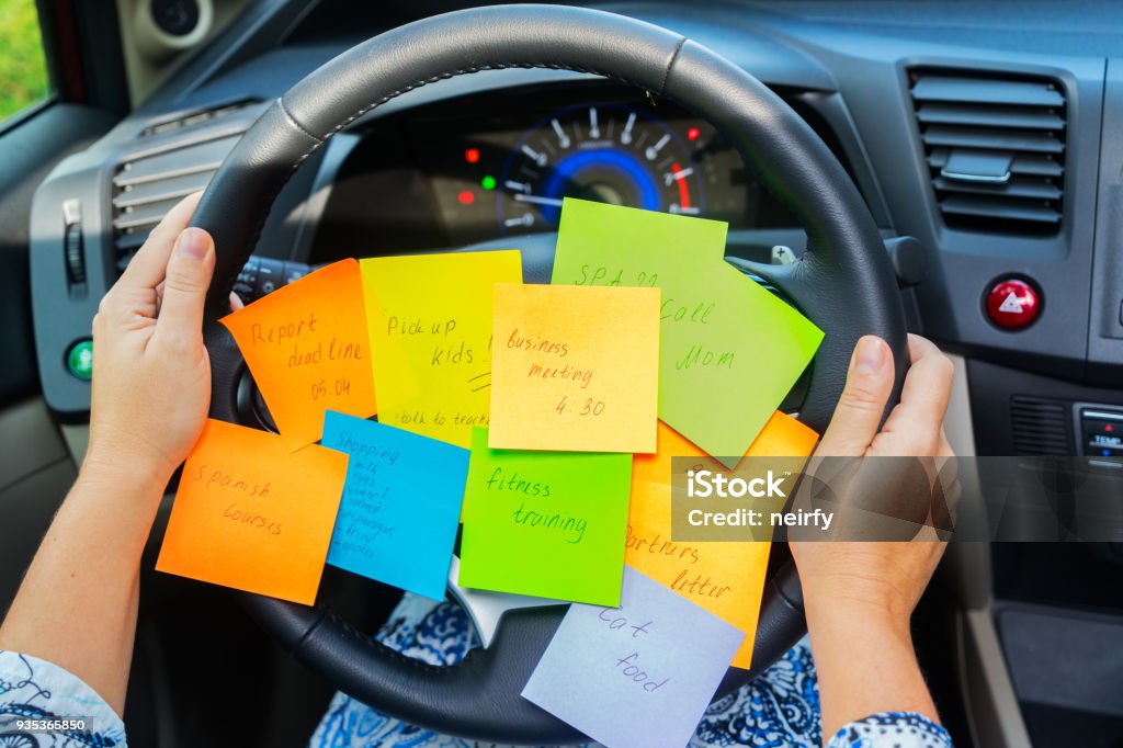 To do list in a car Two hands holding driving wheel and to do list in a car - busy day concept Busy Stock Photo