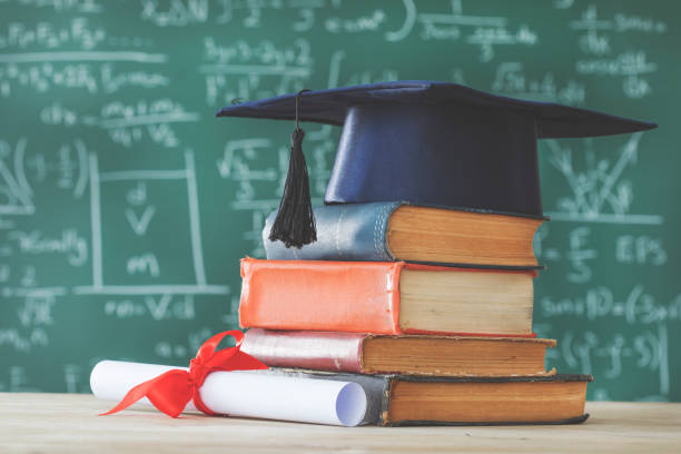 istock Stack books  graduate hat and diploma in front of  green chalkboard 935366856