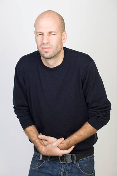 istock Bald man in navy sweater doubled over with a stomach ache 93537142