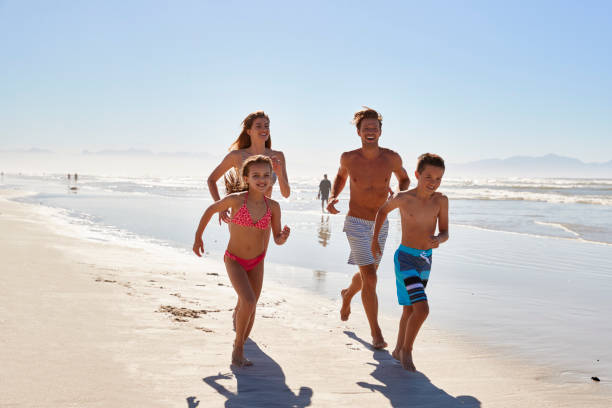 istock Family On Summer Vacation Running Along Beach Together 935372726