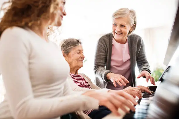 Photo of A girl with mother and grandmother playing the piano.