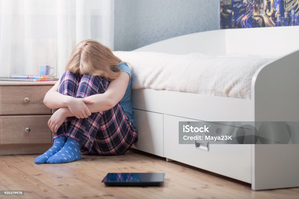 sad teenager girl with scales on floor Teenage Girls Stock Photo