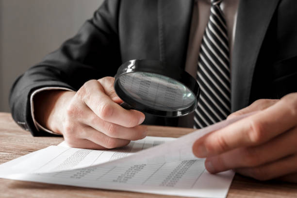 Businessman holding magnifying glass zoom and analyzing financial indicators