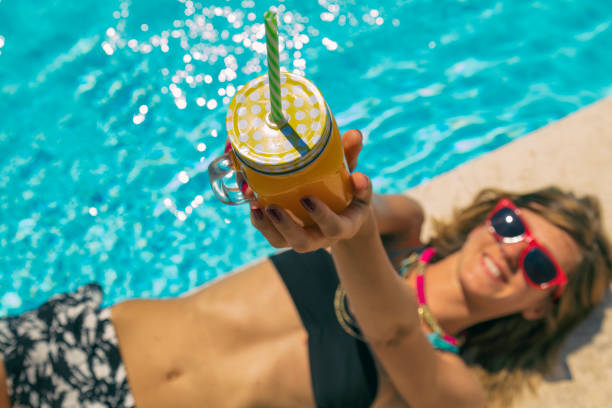 Cute attractive woman on the swimming pool drinking juice. Summer concept. Focus on jar. Cute attractive woman on the swimming pool drinking juice. Summer concept. Focus on jar. healthy slim fit in bikini stock pictures, royalty-free photos & images