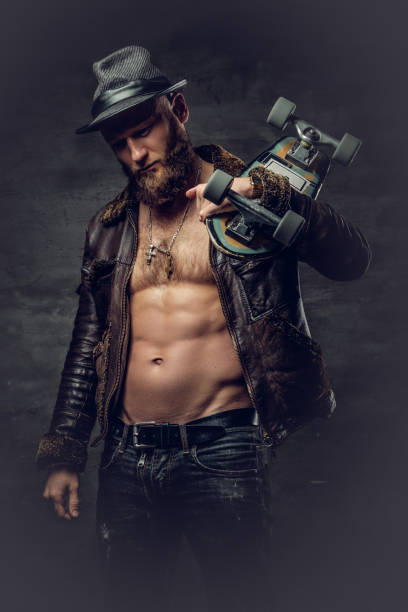 istock Bearded male dressed in leather jackett holds skateboard. 935402736