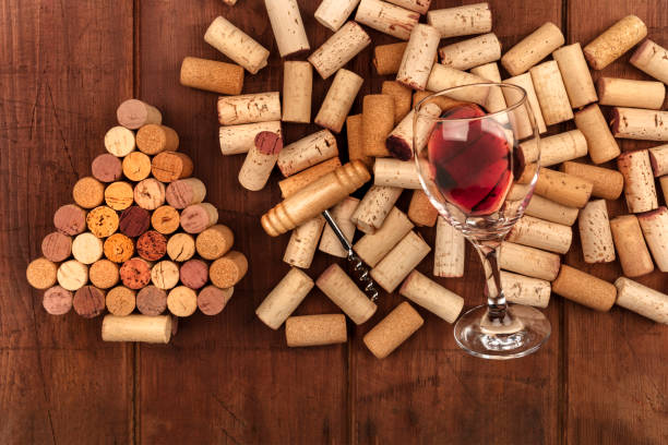 istock Glass of red wine with corks and corkscrew on a dark rustic background, with a handmade Christmas tree and copy space 935405436