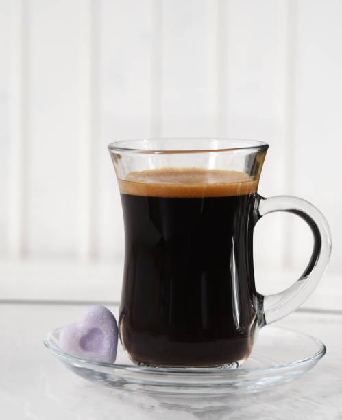 Espresso. Glass cup of espresso with sugar in the form of heart on a light background
