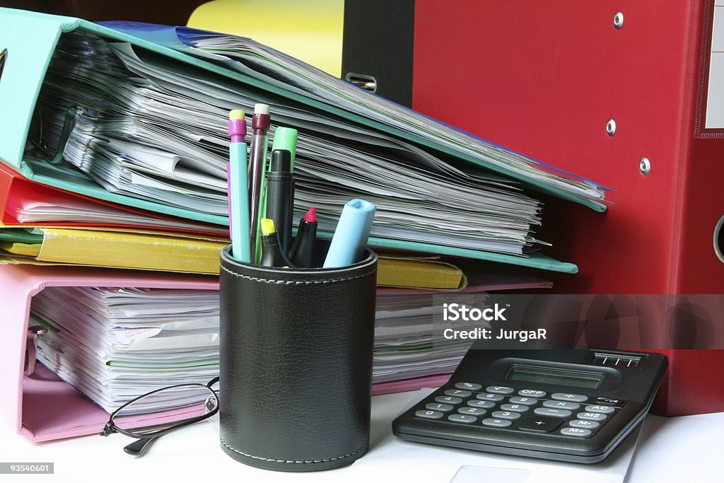 Carpetas con documentos y bolígrafos en un confuso escritorio - Foto de stock de Archivar documentos libre de derechos