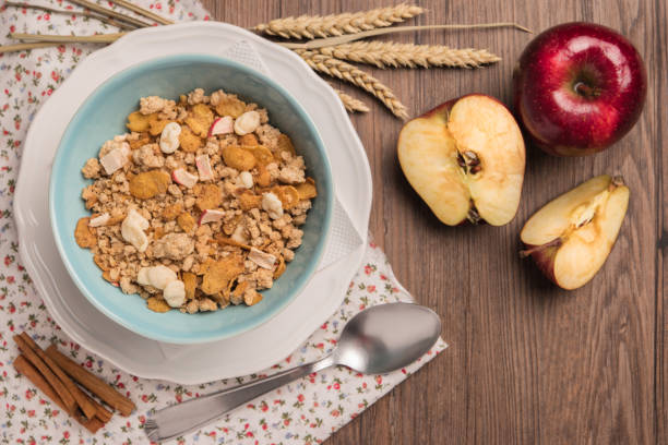 Healthy breakfast with muesli, red apple and cinnamon on rustic wooden table. Top view with copy space.