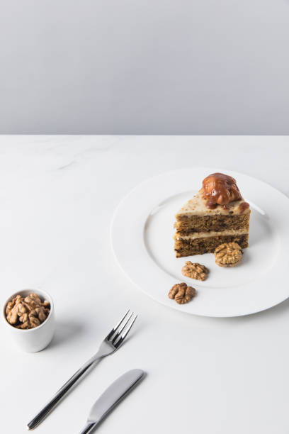 istock Cake on plate with bowl of walnuts on white table 935406940