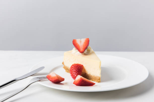 istock Cheesecake with sliced strawberries on plate with cutlery 935407314