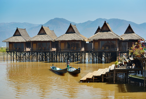LAKE INLE, MYANMAR - FEBRUARY 27, 2015: Burmese thatched roof bungalows on stilts on Lake Inle. They are part of popular hotel resort in the middle of the lake Inle, Myanmar.