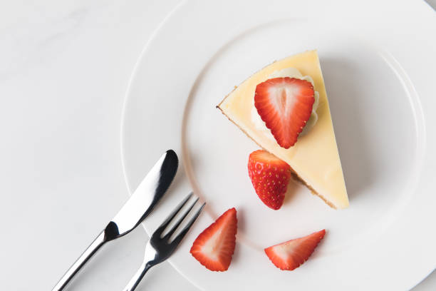 istock Plate with cheesecake surrounding by sliced strawberries 935407518