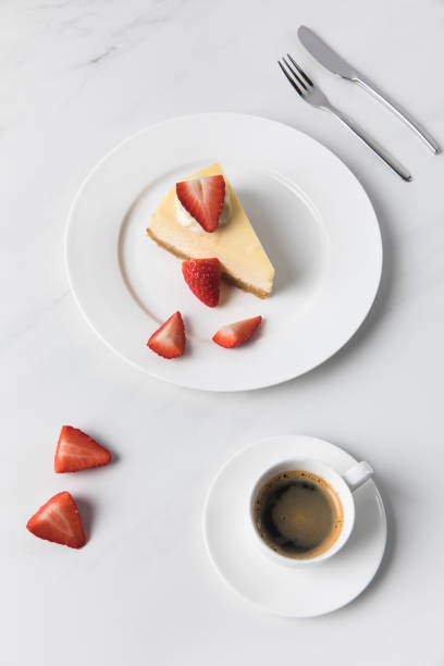 istock Coffee cup with cheesecake and sliced strawberries on plate 935407772