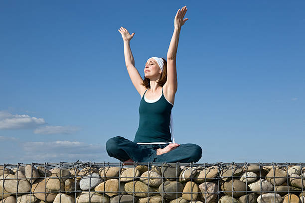 mujer haciendo ejercicios de yoga en la parte superior de una pared de piedra - stone wellbeing zen like blue fotografías e imágenes de stock