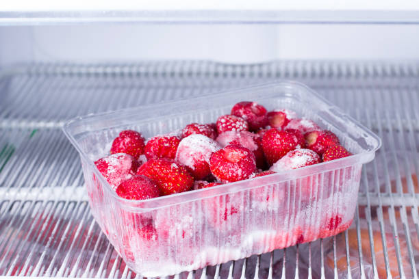 istock Frozen strawberries in a plastic container in the freezer 935411162