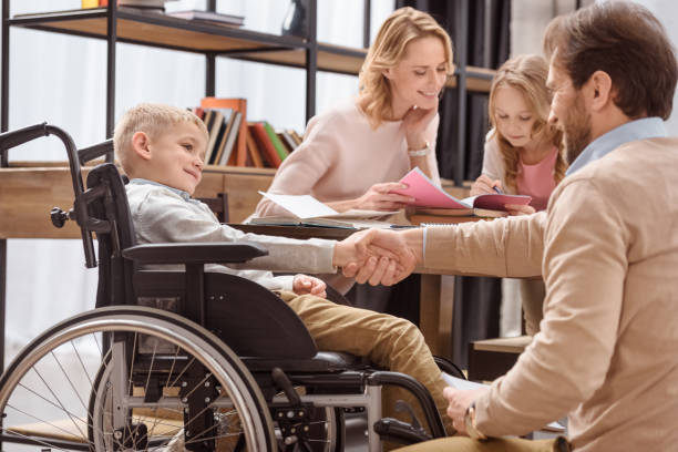 istock father and son on wheelchair shaking hands 935411264