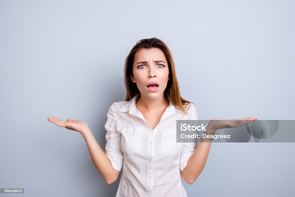 Really?! Shocked and frustrated young lady in formal wear is surprised, standing isolated on the light background, holding copy space Women Stock Photo