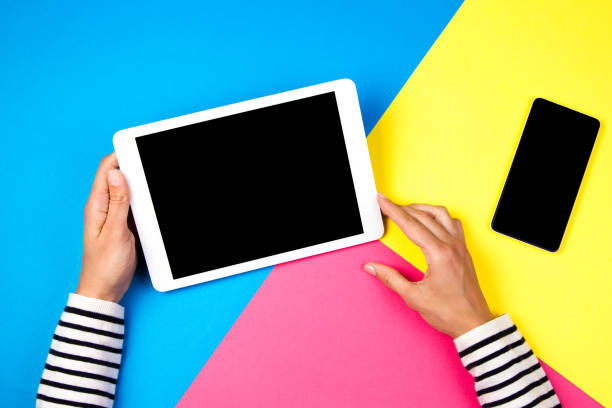 istock Woman's hands with tablet computer and smartphone on colorful background. 935428724