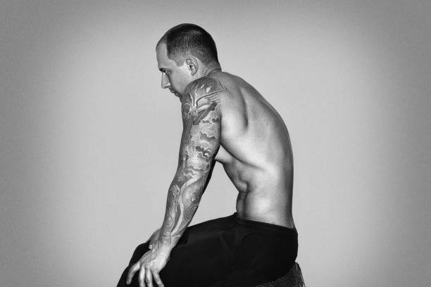 мышечный человек делает вакуумное упражнение - muscular build men tattoo human arm стоковые фото и изображения
