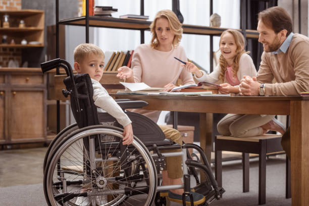 istock sad boy on wheelchair looking at camera and his relatives laughing 935432642