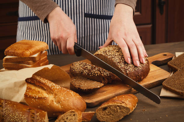 istock Woman cutting bread on wooden board 935444716