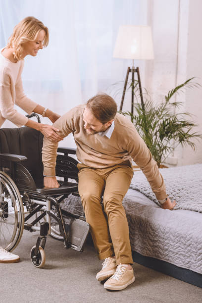 istock wife helping husband with disability sit on wheelchair 935467960