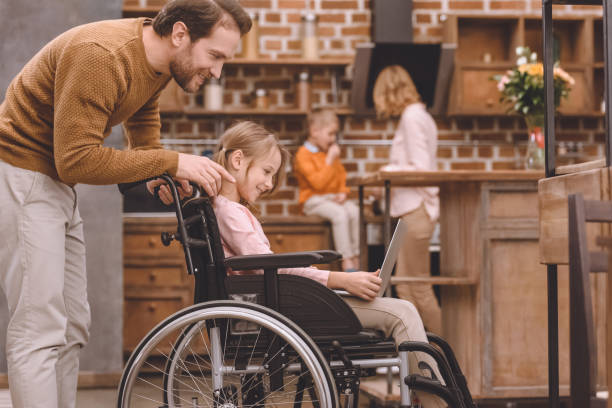 istock side view of happy father looking at smiling disabled daughter using laptop at home 935483068