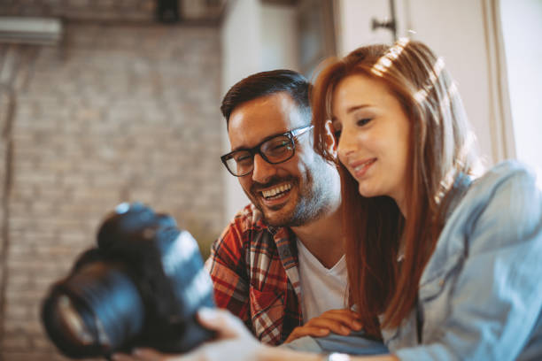 istock Young couple looking photos on the camera at home 935483164