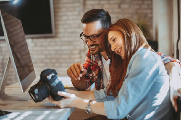 istock Young couple looking photos on the camera at home 935483270