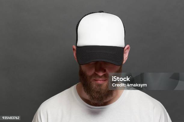 Hipster Handsome Male Model With Beard Wearing White Blank Tshirt And A Baseball Cap With Space For Your Logo Or Design In Casual Urban Style Stock Photo - Download Image Now