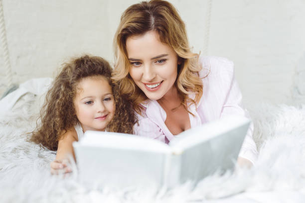 istock mother and curly daughter reading book together 935492106