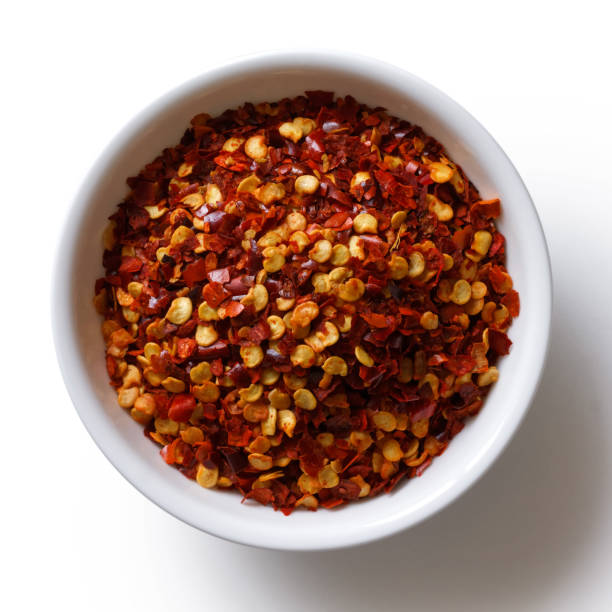 istock Coarsely ground chilli peppers in white ceramic bowl isolated on white from above. 935492172