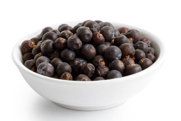 istock Dried juniper berries in white ceramic bowl isolated on white. 935500292