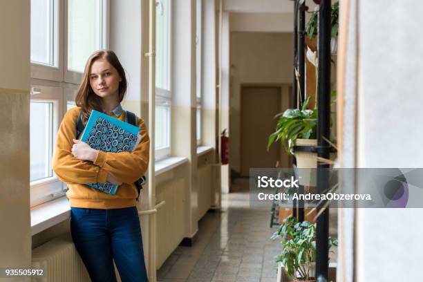 Young Attractive Female High School Student Standing By The Window In The Hallway At Her School Alone Education Concept Stock Photo - Download Image Now