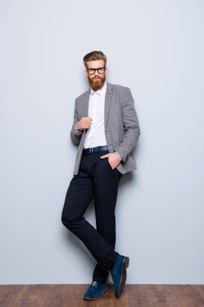 foto a figura intera di giovane bell'uomo in abbigliamento formale con barba rossa e occhiali che si tengono per mano in tasca - pocket suit glasses jacket foto e immagini stock