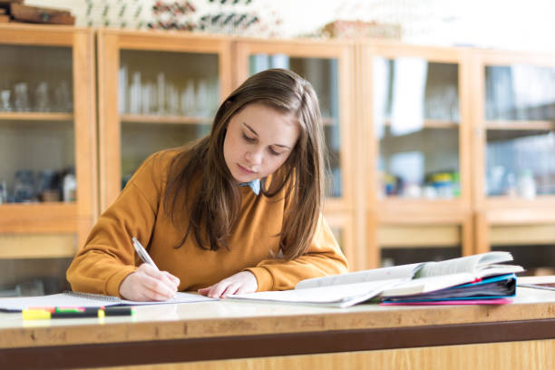 Young female college student in chemistry class, writing notes. Focused student in classroom. Authentic Education concept. stock photo