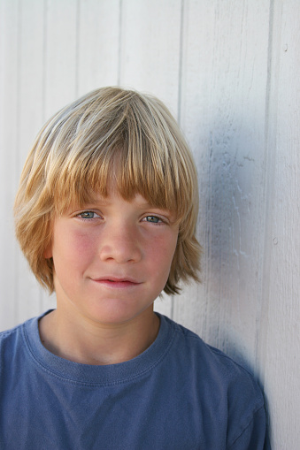 Grade school age boy with a serious expression, wall portrait.