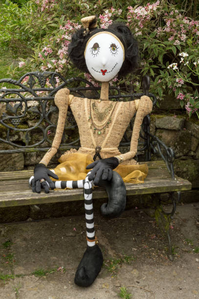 istock Creepy steampunk doll sitting on garden bench. Leg crossed. 935512084